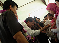 Sekkab Husni Thamrin menyaksikan President & GM Total E&P Indonesie Philipe Armand memasangkan kacamata unt uk seorang pelajar SD Muara Jawa