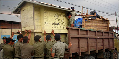 Petugas Satpol PP Kukar mengangkat sebuah rombong milik PKL ke atas truk