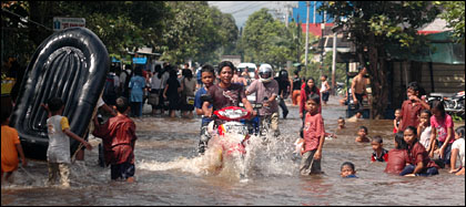 Anak-anak dan remaja di Kelurahan Baru menikmati banjir dengan bermain air di jalan