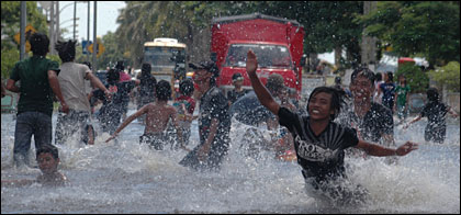 Jalan yang tergenang banjir tetap menjadi tempat menarik bagi anak-anak maupun remaja untuk bermain air