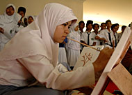 Seorang pelajar putri tampak asyik praktek melukis di atas kanvas